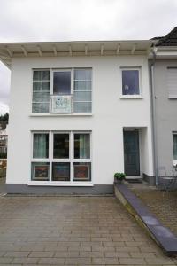 a white house with windows and a brick patio at Ferienhaus Ahrgalerie in Bad Neuenahr-Ahrweiler