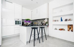 a white kitchen with stools at a counter at 3 Bedroom Lovely Home In Dugi Rat in Dugi Rat +47 photos