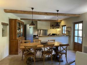 a kitchen and dining room with a wooden table and chairs at Les Demeures Azélie & SPA in Chaudebonne