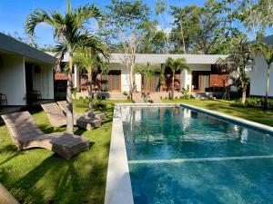 a swimming pool with two chairs and a house at Tropical Almond Villa in Uluwatu