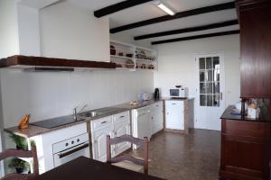 a kitchen with white cabinets and a sink in it at Casa Do Atlântico in Rosário-Lagoa