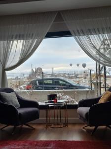 sala de estar con 2 sillas y ventana grande en İclal villa cappadocia, en Uchisar