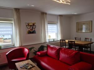 a living room with a red couch and a table at Pilgrims "Bert" moderne Wohnung 2 SZ top wifi in Meschede