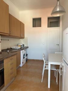 a kitchen with a white table and a white refrigerator at Garden Campo de Ourique Guest House - Hostel in Lisbon