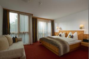 a hotel room with a large bed and a couch at Hotel Montafon Moments in Sankt Gallenkirch +55 photos