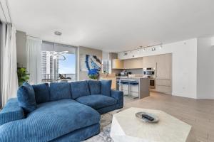 a living room with a blue couch and a kitchen at Hyde Beach House - 2BD-2BA MANSION WITH DIRECT OCEAN VIEW, Resort Amenities, Rooftop Pool and Hot tub, Tennis court, few min walk to the ocean in Hollywood