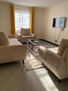 a living room with two couches and a tv at Olive Homes Stylish 3 Bdrm Suites - 07 in Nakuru