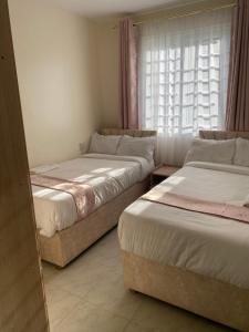 a room with three beds and a window at Olive Homes Stylish 3 Bdrm Suites - 07 in Nakuru
