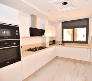 a kitchen with white cabinets and a stove top oven at Appartement Biela in Al Hoceïma