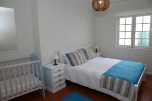 a bedroom with a bed and a crib and a window at Casa Do Atlântico in Rosário-Lagoa