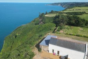 プルーアにあるMaison vue exceptionnelle mer sur les falaises de Plouha, Côtes d'Armorの水辺の丘の上の白い建物の空中風景