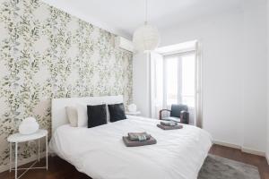 a bedroom with a white bed with a green floral wallpaper at Baixa Chiado LUXURY BEDROOMS in Lisbon
