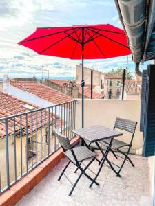 a table and two chairs with a red umbrella on a balcony at Studio cosy - 2 pers - Béziers - Centre - Terrasse - Clim in Béziers
