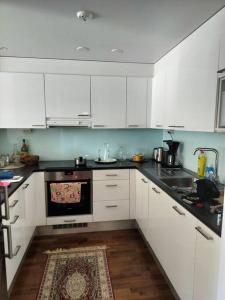 a kitchen with white cabinets and a stove top oven at Kolmio, parvekkeet, meri, sauna ja keskustassa! in Helsinki +2 photos