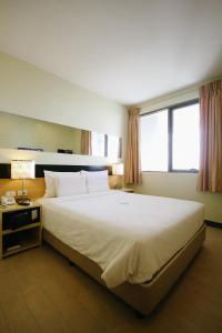 a bedroom with a large white bed with two windows at Go Hotels Iloilo in Iloilo City