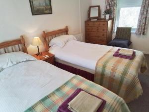 une chambre avec deux lits et une chaise et une commode dans l'établissement Dairy Cottage Newcastle Emlyn, à Newcastle Emlyn
