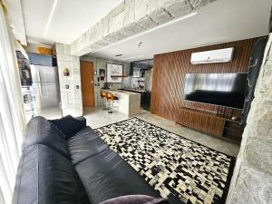 SPOT · Cobertura c/hidro em Aguas Claras, SPOT Apartments في برازيليا: غرفة معيشة مع أريكة جلدية ومطبخ