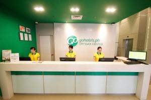 two men in yellow shirts standing at a counter at Go Hotels Ortigas Center in Manila