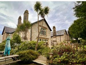 an old stone house with a palm tree in front of it at 2 Bed Lodge - Sleeps 4 - Pets - Pool - Garden in Penzance
