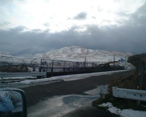uma estrada com uma montanha coberta de neve ao fundo em Mizubaso em Gujo