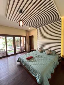 a bedroom with a large bed with a wooden ceiling at Riverside Villa Tanah Lot by Smart Digital in Munggu