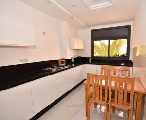 a kitchen with white cabinets and a table and chairs at Appartement Riyam in Al Hoceïma