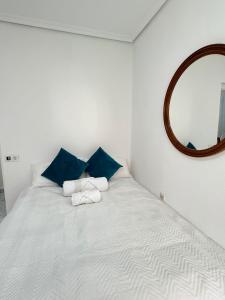 a white bed with blue pillows and a mirror at Habitacion privada in Valencia