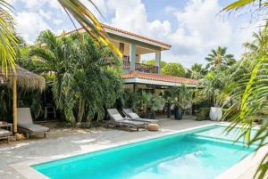 a house with a swimming pool in front of a house at Puur Bonaire Boutique Resort in Belnem