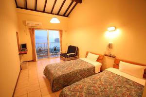 um quarto de hotel com duas camas e uma varanda em Ilmare Unarizaki em Iriomote