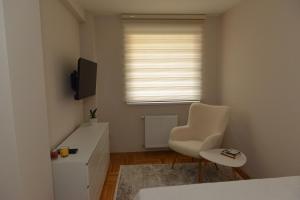 a bedroom with a bed and a chair and a television at Urban Apartman-privatan parking- in Kraljevo