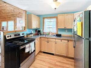 eine Küche mit Holzschränken und einem schwarzen Kühlschrank in der Unterkunft Beach Daze Cottage Brought to you by GetAway Vacations in York