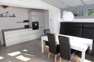 a kitchen and dining room with a white table and chairs at Ostfriesenhuus in Hamswehrum