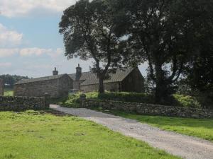 a stone house with a stone fence and a path at Stoney Cliffe Farm in Leek