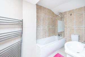 a bathroom with a tub and a toilet and a sink at DAGENHAM 3 and 4 BEDROOMS 2BATHS with Parking in Dagenham +45 photos