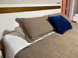 a bed with a blue pillow on top of it at Pousada dos Pássaros in Gramado
