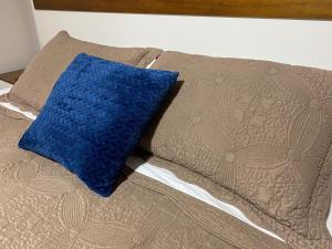 a bed with a blue pillow on top of it at Pousada dos Pássaros in Gramado