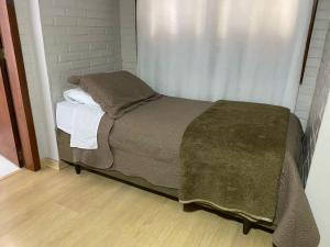 a small bed in a room with a window at Pousada dos Pássaros in Gramado