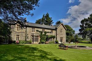 a large stone house with a pond in the yard at Llangattock Park House in Crickhowell