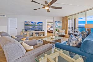 a living room with blue furniture and a ceiling fan at Royal Kahana 1010 in Kahana