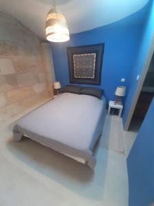 a bedroom with a white bed in a blue room at Maison d'artiste in Saint-Quentin-de-Baron