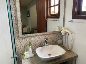 a bathroom with a sink and a mirror at Pousada dos Pássaros in Gramado