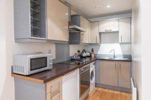 a kitchen with white cabinets and a microwave at 30 Quayside Newcastle in Newcastle upon Tyne