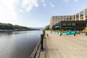 a river with a building and a bridge in the background at 30 Quayside Newcastle in Newcastle upon Tyne