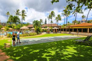 Dos personas de pie en una cancha de tenis en un patio. en Maui Kaanapali Villas 292, en Lahaina