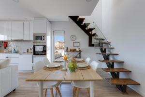 a kitchen and dining room with a table and a staircase at Burgau Village and Sea in Burgau