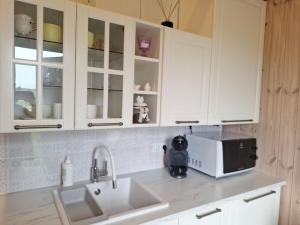 a kitchen with white cabinets and a sink and a microwave at MiNi homes in Piniava