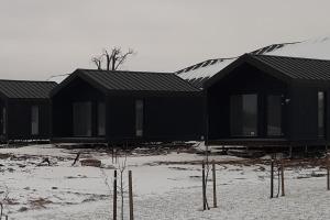 a row of black houses in the snow at MiNi homes in Piniava +3 photos