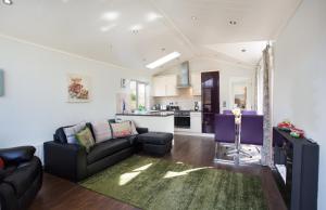 a living room with a couch and a kitchen at Bluebell Lodge - Sleeps 4 Hot Tub Loch & Woodland in Strathpeffer +13 photos