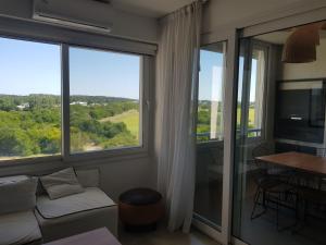 a living room with a couch and large windows at Departamento con vista al Golf Barrio Costa Esmeralda in Costa Esmeralda