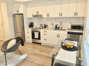 una cucina con armadi bianchi e tavolo in vetro di Central Moodyville Retreat a North Vancouver
